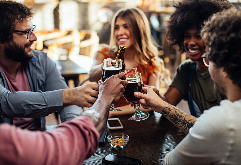 4 friends cheers together on a restaurant patio 